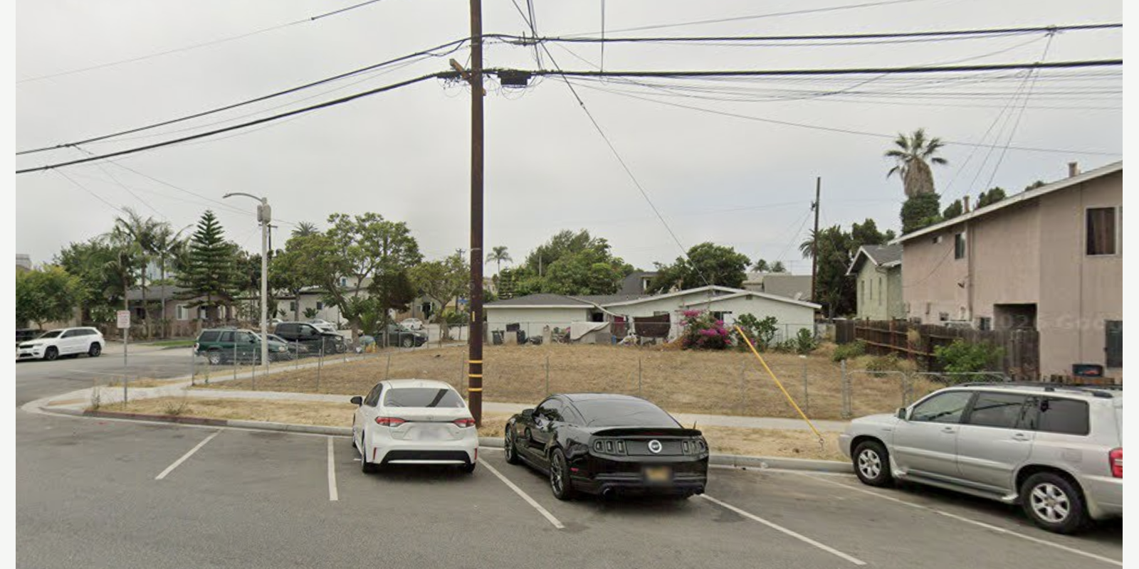 Before: vacant lot behind a chain-link fence prior to habitat work.